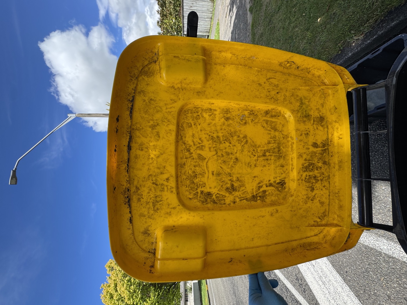 Dirty yellow bin lid before cleaning — grime and staining